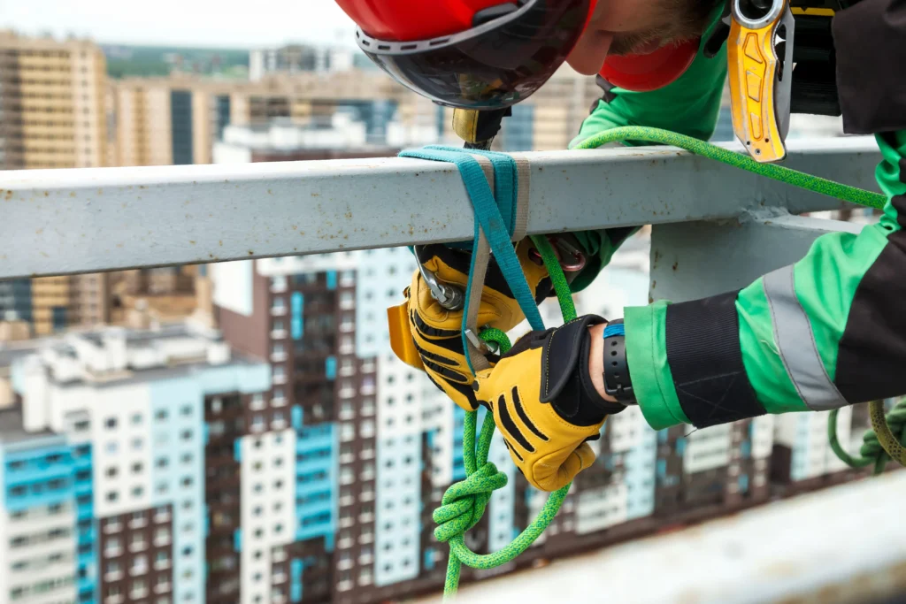Fotografía de cerca de un hombre asegurando su equipo de trabajo en alturas como lo establece la nom 009 stps.