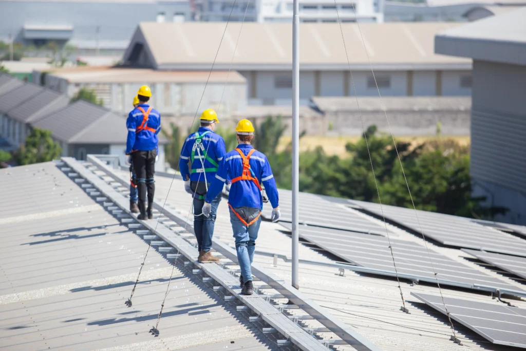 Fotografía de tres personas con camisa azul y casco amarillo para protección como lo dice la nom 009 stps.