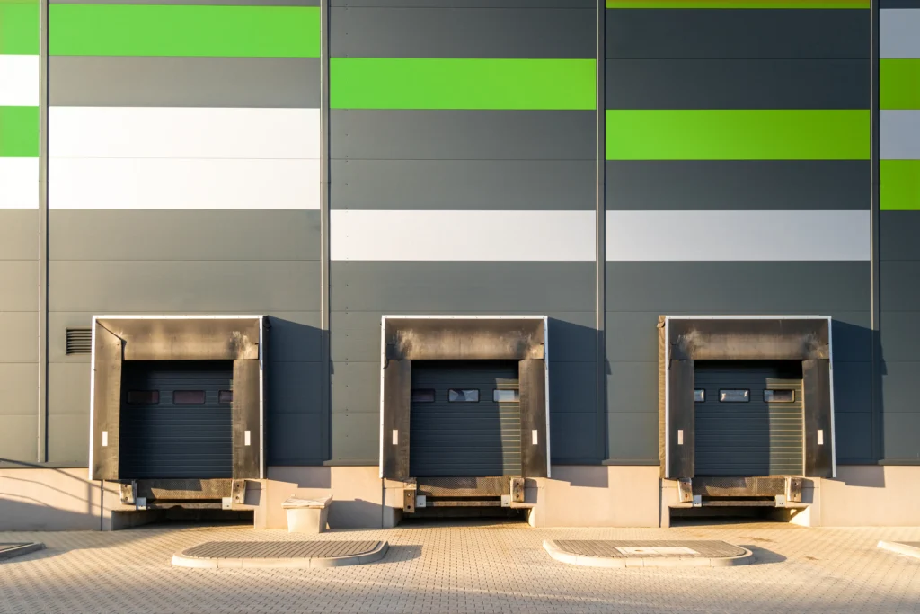 Fotografía de una pared color gris Oxford con verde donde están colocadas puertas seccionales industriales.
