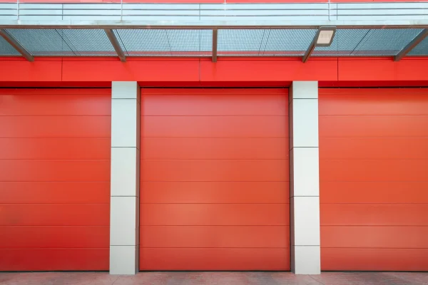 Un almacén de vibrante color rojo con blanco, con una puerta seccional de seguridad completamente cerrada