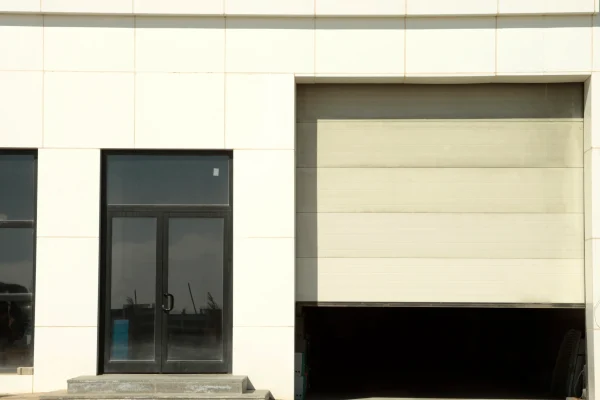 Un edificio moderno exhibe una puerta seccional de láminas anchas y horizontales, parcialmente abierta, demostrando su estética y operatividad.
